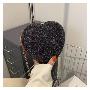 Macro shot of heart-shaped glitter crossbody bag with gold chain and red edge detail