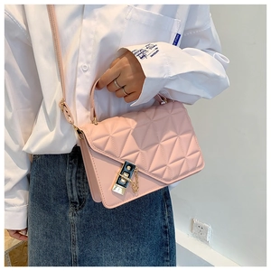Pink quilted crossbody bag with gold hardware shown on a model with white shirt