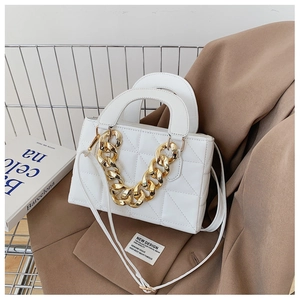 Detailed view of white quilted leather bag with large gold chain on a brown blazer