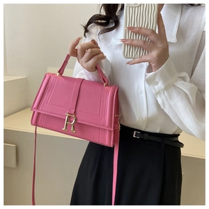 Close-up of pink crossbody bag with gold R-logo clasp and stylish leather texture