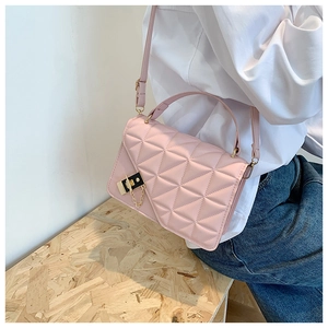 Detail of pink quilted shoulder bag with golden metallic lock and leather strap