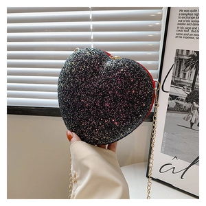 Close-up of a heart-shaped glitter shoulder bag with black sequins and a gold chain strap