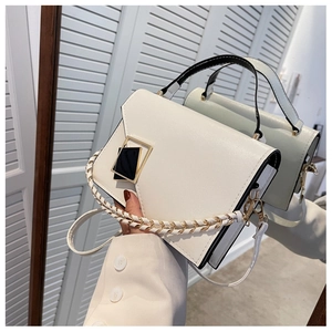 Close-up of white PU leather handbag featuring black handle and gold geometric lock