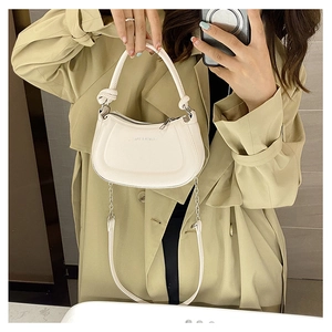 Detail of off-white PU leather handbag with knot handle and chain strap in mirror selfie