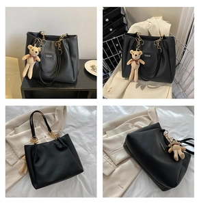 Detail of black PU tote bag with gold chain strap, fashion label, and teddy bear charm