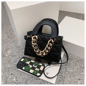 Detail of black quilted handbag with chunky gold chain and flower pattern phone case