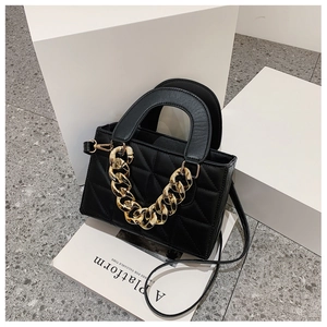 Detail of black quilted handbag with chunky gold chain on magazine for luxury display