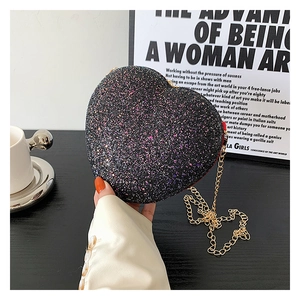 Close-up of heart-shaped black sequin crossbody bag with shiny glitter and golden chain strap