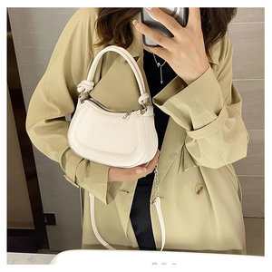 Mirror selfie showing the small cream white crossbody bag with knot handle detail