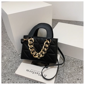Detail of black quilted handbag featuring bold gold chunky chain and metallic clasp