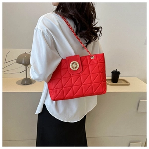 Gros plan du sac matelassé rouge avec boucle dorée et bandoulière chaîne sur modèle