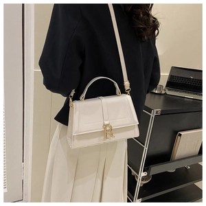 Side view of structured cream PU leather crossbody bag with golden R-shaped metal hardware