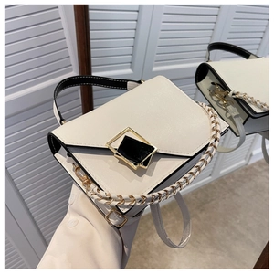 Detail of contrast stitching handbag with gold clasp and chain strap on marble surface