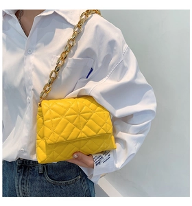 Detail of yellow quilted pattern on soft PU leather bag with bold gold chain strap