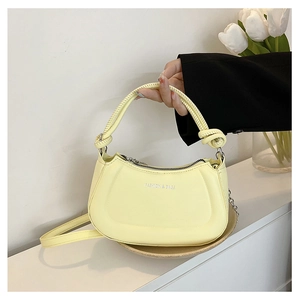 Detail of light yellow leather handbag with knotted handle and silver chain strap