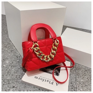 Detail of red quilted shoulder bag with chunky gold chain and premium PU leather texture