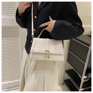 Close-up of white leather handbag featuring a prominent gold metal R-shaped buckle