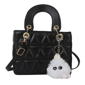 Classic black quilted crossbody handbag with gold hardware and plush charm on white background