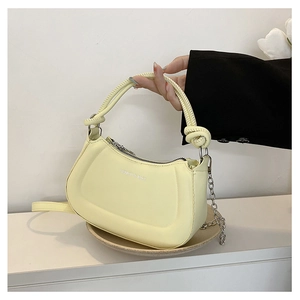 Detailed shot of cream yellow crescent bag with silver chain and knotted handle detail