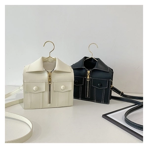 Detail of jacket-shaped crossbody bags in black and white with metal hanger handles