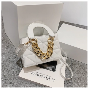 Detail view of quilted white handbag with chunky gold chain and leather shoulder strap