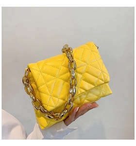 Close-up of bright yellow quilted PU leather bag with chunky gold metal chain strap