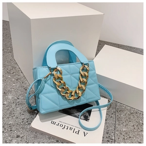 Detailed view of light blue quilted handbag with thick gold chain and crossbody strap