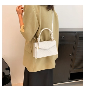 Detail of white embossed leather handbag showing gold hardware and detachable strap