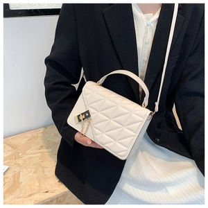 Detail of off-white quilted handbag featuring a golden chain lock and refined PU texture