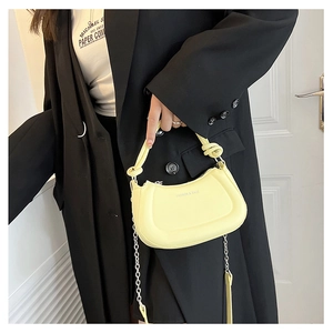 Detail of light yellow hobo bag with a knotted handle and silver chain on model