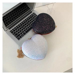 Detail of heart-shaped sequin bags with golden chain straps on white desk