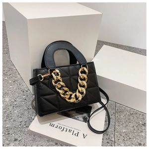 Detail of black quilted handbag featuring a chunky gold chain and premium faux leather texture