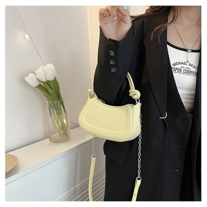 Detailed shot of yellow crescent bag with knotted handle and chain shoulder strap