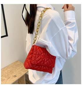 Detail of red quilted shoulder bag featuring chunky gold acrylic chain and soft PU leather