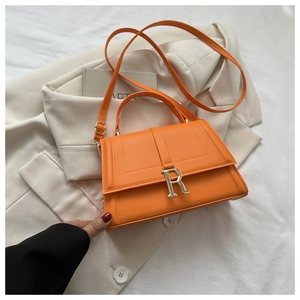Detail of orange quilted handbag with silver R buckle and textured leather finish
