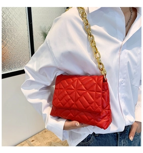 Detailed view of red quilted leather shoulder bag with bold gold acrylic chain link