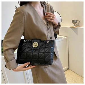 Sac matelassé chic avec boucle dorée évidée porté avec un tailleur marron élégant