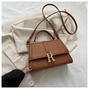 Detailed view of brown leather crossbody bag with elegant gold metal R buckle closure