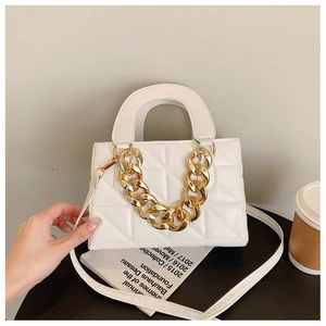 Close-up of white quilted handbag with chunky gold chain handle and faux leather texture