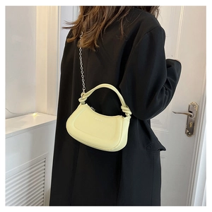 Detail of light yellow half-moon shoulder bag with silver chain strap and ring handle