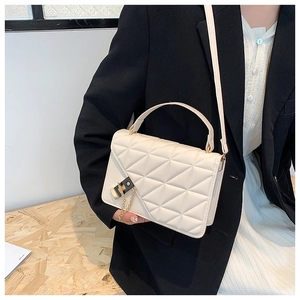 Fashion beige quilted handbag with gold lock shown on a model in a stylish city look