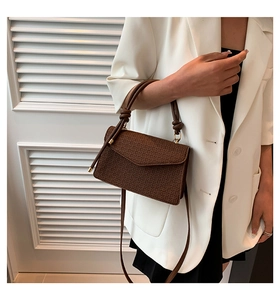 Close-up of brown textured square bag with woven pattern and knotted handle detail