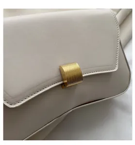 Detailed close-up of beige shoulder bag featuring a textured finish and gold metal clasp