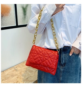 Detail of red quilted PU leather shoulder bag with bold gold acrylic chain link strap