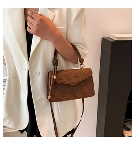 Close-up of brown textured crossbody bag with woven pattern and gold metal hardware