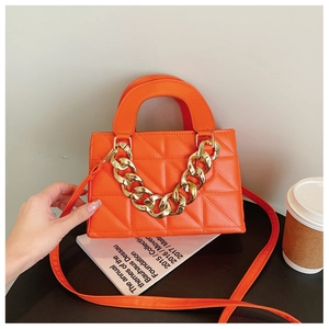 Close-up of bright orange quilted handbag featuring a chunky gold chain and PU texture