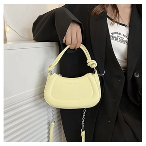 Close-up of yellow crescent moon bag with twisted rope handle and silver chain strap