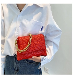 Detail of red quilted PU leather shoulder bag with decorative gold acrylic chain strap