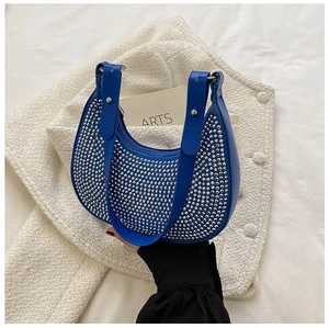 Detailed shot of royal blue underarm bag featuring silver rivets on tweed background