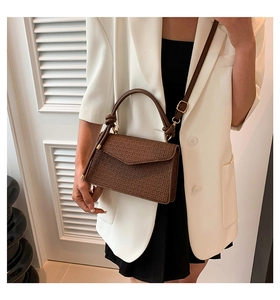 Detail of caramel brown crossbody bag with woven texture and gold hardware accents